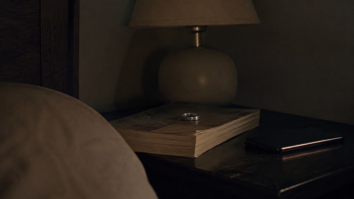 Smart ring on a bedside table at night beside a phone, used for sleep tracking